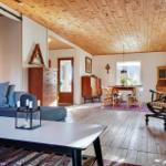 Living and dining area with wooden ceiling, sofa, rocking chair, and dining table.