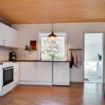 Kitchen with white cabinets, wooden floor, and window to the garden.