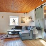 Living room with sofa, coffee table, and wooden floor. Bedroom with bed visible.