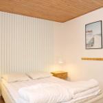 Bedroom with bed, nightstands, and striped wall. Wall art and straw bag hang on the wall.