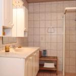 Bathroom with shower, sink, and mirror cabinet. Wooden stool and shower curtain visible.