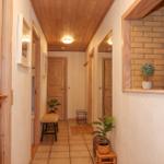 Hallway with wooden ceiling, doorways, and plants along the walls.