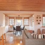 Living and dining area with wooden ceiling, sofa, table, and windows.