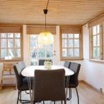 Dining room with round table, chairs, and wooden windows. Ceiling and floor are wooden.
