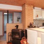 Kitchen with wooden ceiling, wood stove, and view into the bathroom.