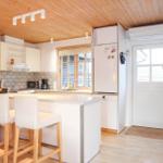 Kitchen with wooden ceiling, refrigerator, window, and bar stools.