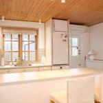 Kitchen with wooden ceiling, refrigerator, sink, and seating at the counter.