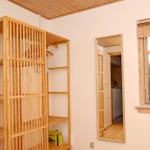 A room with wooden shelving, door, and window. Wooden ceiling and wall color.