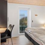 Bedroom with bed, desk, and balcony door. Wooden ceiling and wall art visible.