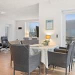 Dining area with table and chairs, living space with sofa and staircase in background.