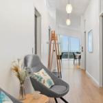 Hallway with gray chairs, wooden floor, and view into dining area with sea view.