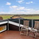 Terrace with two wooden chairs and view of fields and sky.