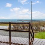 Wooden terrace with view of the sea and a lighthouse in the distance.