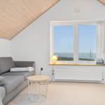 Living room with sofa, sea view window, and wall-mounted TV.