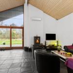Living room with fireplace, TV, and black leather furniture. Large glass door to garden.