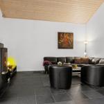 Living room with wooden ceiling, sofa, chairs, and wood stove.