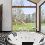 Jacuzzi with view of garden featuring slide and play equipment.