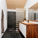Bathroom with wooden ceiling, glass block wall, and wooden vanity.