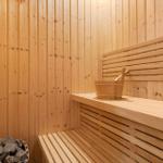 Sauna with wooden bench and bucket. Stones in stove. Wooden walls.