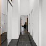 Hallway with white walls, dark floor, and door to living room with fireplace.