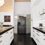 Kitchen with white cabinets, black countertops, and stainless steel refrigerator.