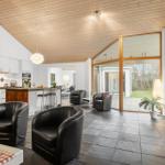Modern open kitchen and living area with fireplace, black chairs, and wood ceiling.