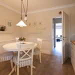 Esszimmer mit runden Tisch und Stühlen, Küchenbereich und Tür zum Wohnzimmer.