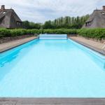 Pool mit Holzumrandung und Dachhäuser im Hintergrund.