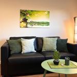 Ein Wohnzimmer mit einem schwarzen Sofa, Kissen und einer Wanddekoration.