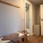 Eingangsbereich mit Holzbank, Hakenwand und Blick in Bad und Schlafzimmer.