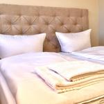 Ein Bett mit weißer Bettwäsche und zwei Kissen. Auf dem Bett liegen gefaltete Handtücher.