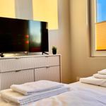 Schlafzimmer mit Bett, Fernseher und Fenster mit Jalousie.