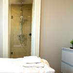 Schlafzimmer mit Dusche und Schrank. Handtuch auf Bett. Pflanze auf Schrank.