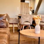 Wohn- und Essbereich mit Sofa, Stühlen und Tisch. Holzfußboden und Dekorationsgegenstände.