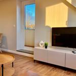 Wohnzimmer mit Fernseher, TV-Schrank und Fenster mit Blick auf Bäume.