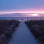 Pfad führt zum Strand bei Sonnenuntergang mit farbigen Himmel und Meer.