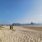 Strand mit Steg und Strandkorb. Klare See und blauer Himmel.