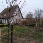 Haus mit strohgedecktem Dach und Garten im Vordergrund.