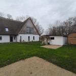 Haus mit Dach und Garten. Nebengebäude und Holztor sichtbar.