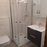 Badezimmer mit Dusche, Waschbecken und Toilette.