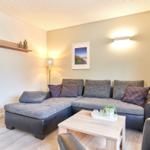 Ein Wohnzimmer mit einem grauen Sofa, einem Holztisch und einer Wandlampe.