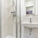 Dusche mit Duschbrause und Waschbecken mit Spiegel