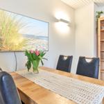 Esszimmer mit Holztisch, Stühlen und Bild an der Wand.