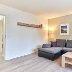 Wohnzimmer mit Sofa, Couchtisch und Holzregal an der Wand.