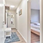 Flur mit Kleiderhaken und Tisch. Im Hintergrund Schlafzimmer mit Bett.