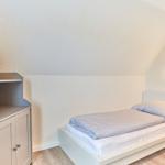 Ein Schlafzimmer mit einem Bett, einem Schrank und einer Wandlampe.