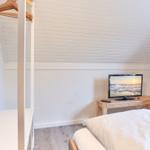 Schlafzimmer mit Bett, Kleiderständer und Fernseher auf Holztisch.