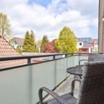 Terrasse mit Tisch und Stühlen, Blick auf Dächer und Bäume.