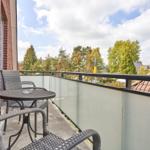 Balkon mit Tisch und Stühlen, Blick auf Bäume und Dächer.