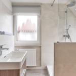 Badezimmer mit Dusche, Waschbecken und Fenster mit Rollladen.